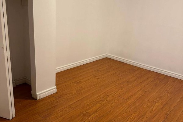 Corner of an empty room with wood laminate flooring and white walls and baseboards. - Basement - 75 Windrush Trail, Toronto