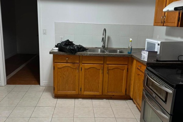 Basement kitchen with oak cabinets, double sink, microwave, and stainless steel stove. - Basement - 75 Windrush Trail, Toronto