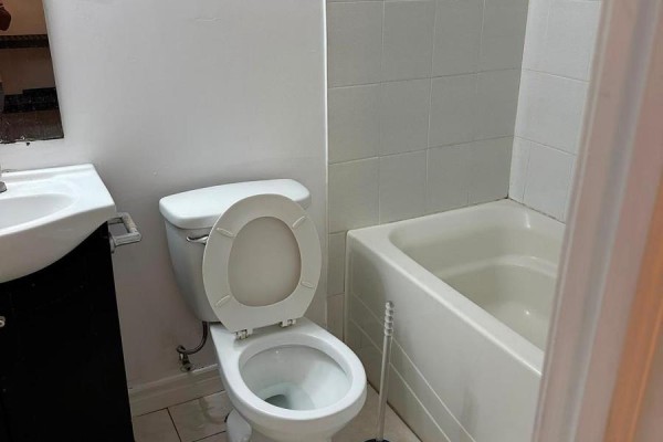 Basement bathroom with a toilet, bathtub, white tiled walls, and a vanity. - Basement - 75 Windrush Trail, Toronto