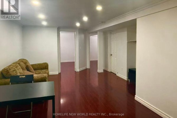 Spacious basement living area with dark wood floors and multiple doorways. - Basement - 84 James Edward Drive, Markham