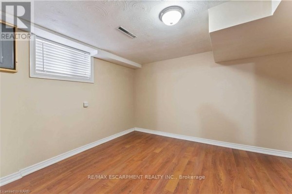 White kitchen cabinets, countertops, refrigerator, and stove with a view into a bathroom. - Basement - 864 Upper Ottawa Street, Hamilton