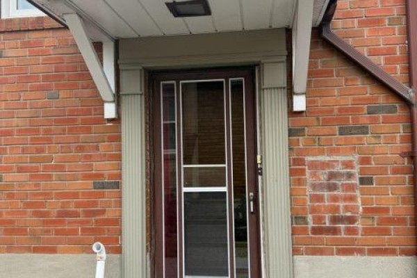 Close-up of the main entrance door with brick surround and a white awning. - Basement - 9 Japonica Road, Toronto
