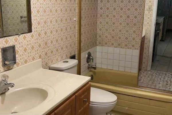 Bathroom with vanity, toilet, and bathtub with yellow trim and patterned wallpaper. - Basement - 91 Markham Street, Toronto