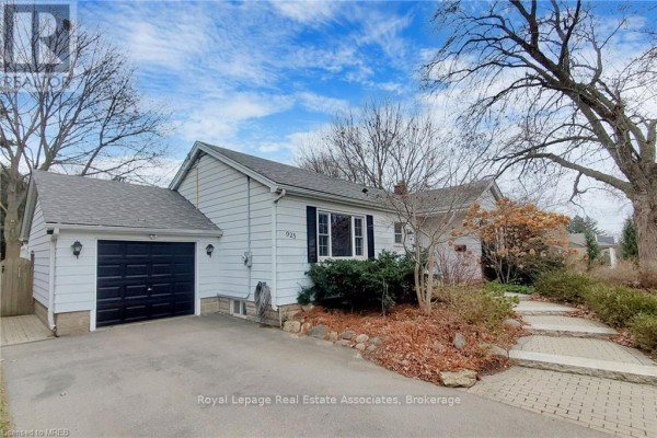 Side view of the bungalow showing the attached garage, walkway, and surrounding greenery. - Basement - 925 Kingsway Drive, Burlington