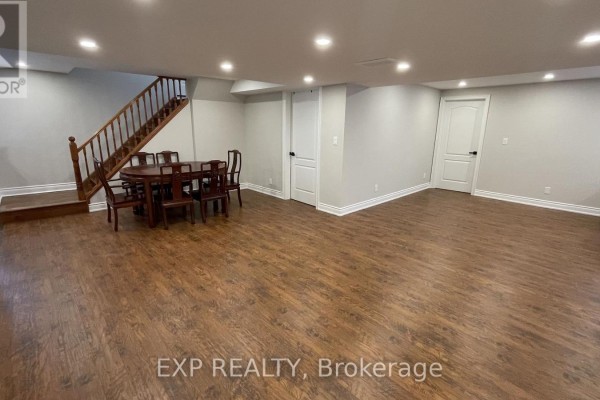 Basement with wood-look flooring, a wooden dining set, and doors to other rooms. - Basement - 94 Lensmith Drive, Aurora