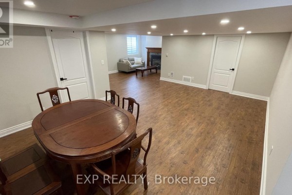 Basement with a dining area, wooden flooring, and a glimpse of a living room. - Basement - 94 Lensmith Drive, Aurora