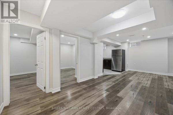 Basement living space with grey wood-look flooring, white walls, and double doors. - Basement 1 - 277 Gibson Circle, Bradford West Gwillimbury