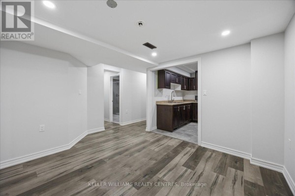 Unfurnished basement room with white walls, grey wood laminate flooring, and two doorways. - Basement 2 - 277 Gibson Circle, Bradford West Gwillimbury