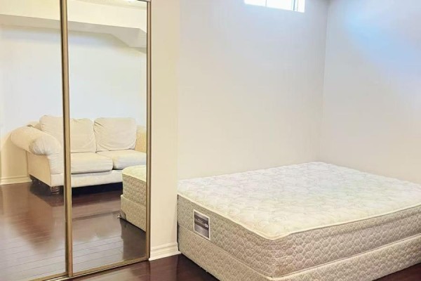 Basement bedroom with mattress on floor, sofa, and oval coffee table. - Basement A2 - 50 Dowling Circle, Markham