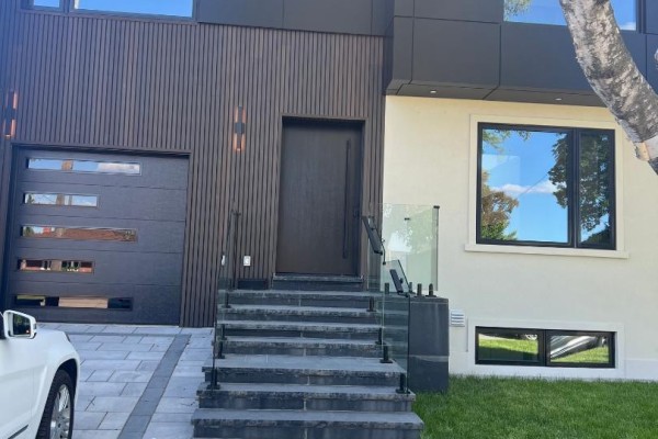 Front entrance with dark wood door, garage, stone steps, and glass railings. - Basement Apartment - 50 Brawley Avenue, Toronto