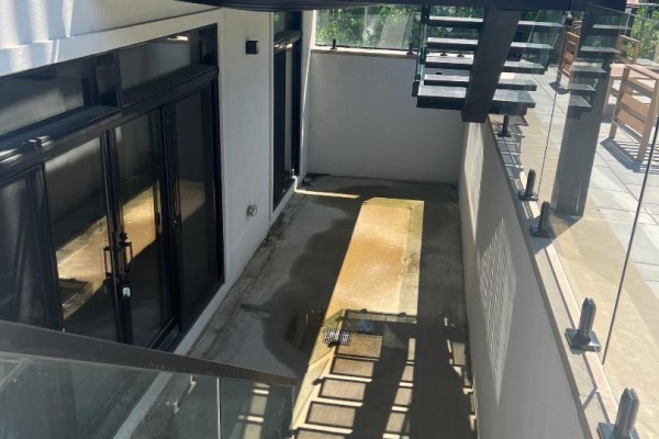 Concrete patio with glass railings and outdoor stairs leading to a balcony area. - Basement Apartment - 50 Brawley Avenue, Toronto
