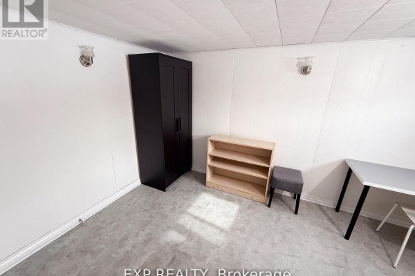 View of the room showing a wardrobe, shelving unit, and a small chair. - Basement Room 3 - 500 Drewry Avenue, Toronto