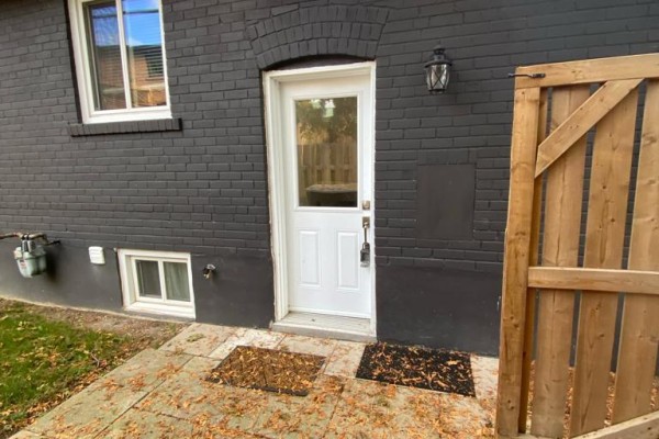 Exterior back door with glass insert and adjacent wooden fence and brick wall. - Basemnt - 112 Walter Avenue, Newmarket