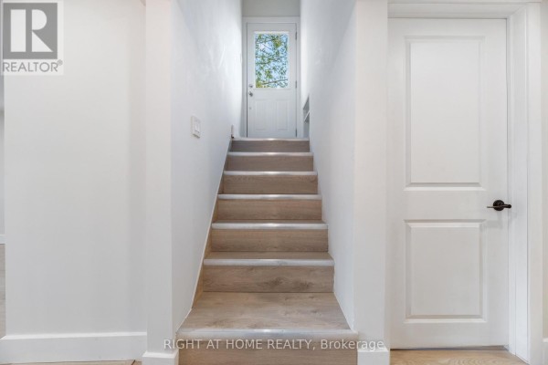 Interior staircase leading down with white walls and wooden-look flooring. - Basemnt - 112 Walter Avenue, Newmarket