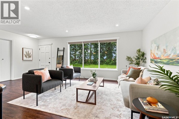 Living room with plush seating, coffee table, and a large window view. - Bellavance Acreage, North Battleford Rm No  437