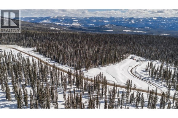 Aerial view of a paved road through a vast snow-covered forest with distant mountains. - Black Forest Way Lot# 5, Big White