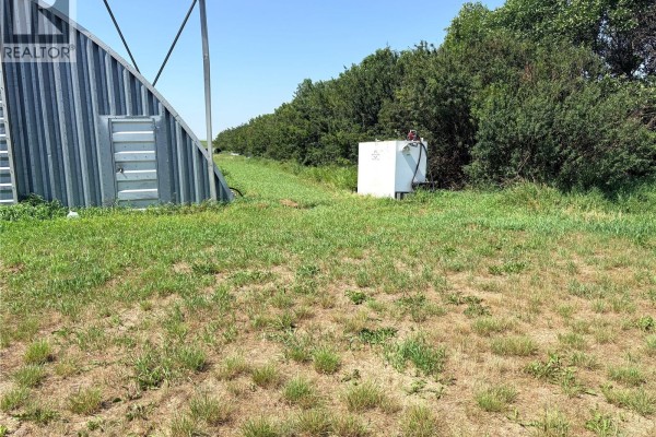 Side view of a Quonset hut with a white storage tank and green trees in the background. - Bryden Acreage Nw 08-32-19 W3rd, Winslow Rm No  319