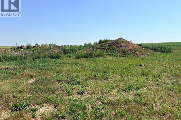 A dirt mound and overgrown grass in a field with scattered debris in the distance. - Bryden Acreage Nw 08-32-19 W3rd, Winslow Rm No  319