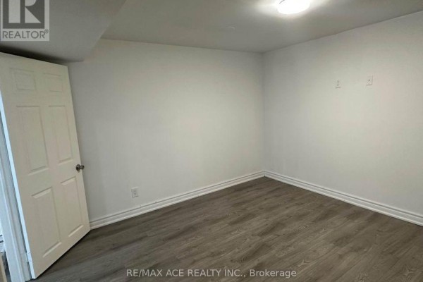 Unfurnished room with white walls, grey laminate flooring, and white door. - Bsmt - 11 Seasons Drive, Toronto