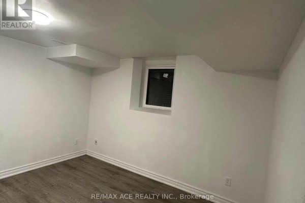 Unfurnished room with white walls, grey laminate flooring, and small window. - Bsmt - 11 Seasons Drive, Toronto