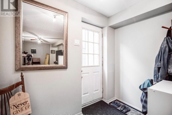 Interior view of a small foyer with a white door, a wooden mirror and a chair. - Bsmnt - 201 Biscayne Boulevard, Georgina