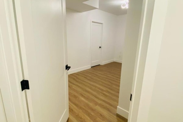 View through an open doorway into a room with white walls and wood-look flooring. - Bsmnt - 684 Fenwick Way, Ottawa