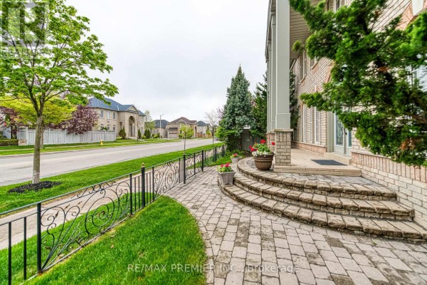 Stone walkway and steps leading to the entrance of a brick house with a wrought iron fence. - Bsmt - 1 Johnswood Crescent, Vaughan