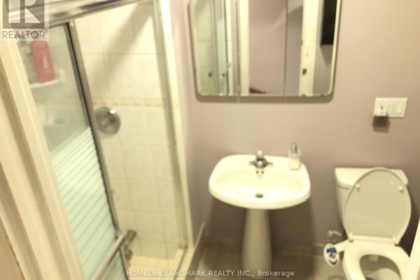 A small bathroom with a pedestal sink, toilet, and a glass-enclosed shower with white tiles. - Bsmt - 10 Oscar Court, Toronto