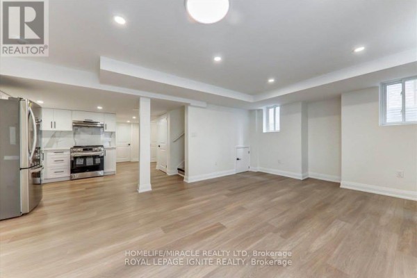 Wide view of a basement rec room and kitchen, showcasing neutral tones and ample lighting. - Bsmt - 1006 Pelican Trail, Pickering