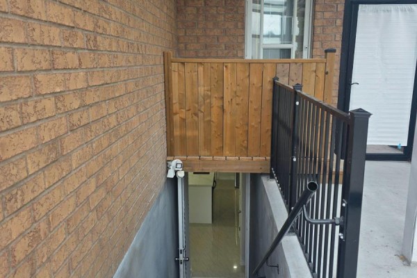 Exterior view of basement entrance with stairs, metal railing and wooden fence. - Bsmt - 1022 Glenbourne Drive, Oshawa