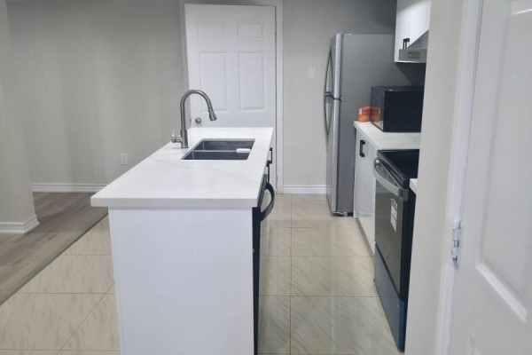 Basement kitchen with white island, stainless steel appliances, and light grey walls. - Bsmt - 1022 Glenbourne Drive, Oshawa