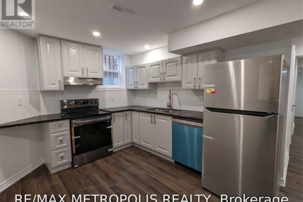 A basement kitchen with white cabinets, stainless steel appliances, and dark countertops. - Bsmt - 119 Tom Edwards Drive, Whitby