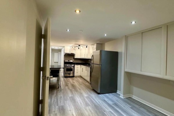 Open concept kitchen with white cabinets, stainless steel appliances, and a dining area. - Bsmt - 13 Sorauren Avenue, Toronto