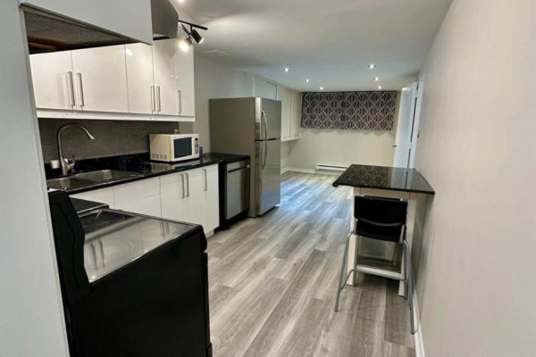 View of the kitchen and dining area with a breakfast bar and stool. - Bsmt - 13 Sorauren Avenue, Toronto