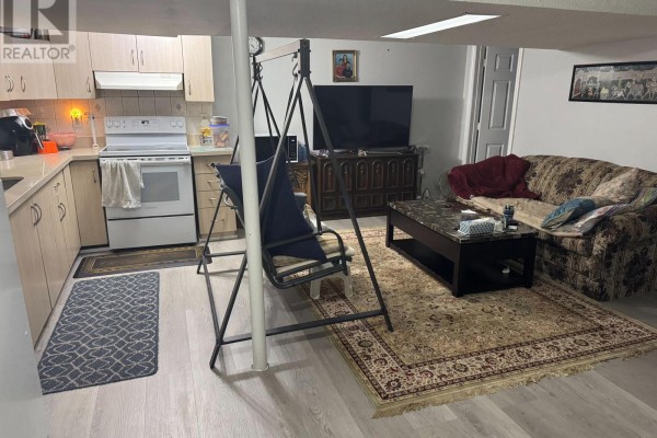Basement living area with sofa, coffee table, swing, and kitchen counter. - Bsmt - 147 Morton Way, Brampton
