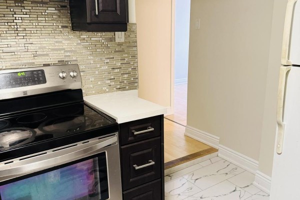 Basement kitchen showing a stainless steel range, dark cabinets, and marble-look tile flooring. - Bsmt - 15 Berkham Road, Toronto
