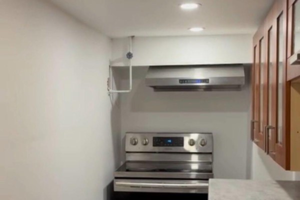 A stainless steel stove and range hood are centered in a small kitchenette. - Bsmt - 15 Cree Avenue, Toronto