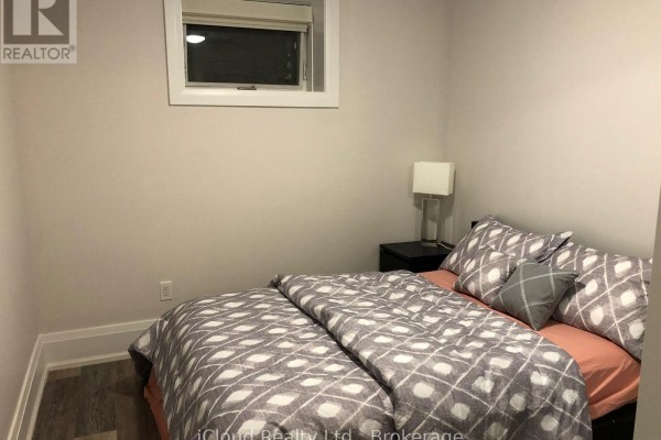Second bedroom with a queen-size bed, patterned bedding, and a small window. - Bsmt - 154 Delhi Avenue, Toronto