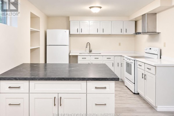 Basement kitchen with white cabinetry, a grey island, white appliances, and laminate flooring. - Bsmt - 156 Major Buttons Drive, Markham