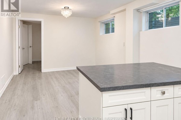 Basement living area with view into hallway, beige walls, laminate flooring, and two small windows. - Bsmt - 156 Major Buttons Drive, Markham