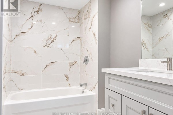Basement bathroom with a white tub, marble-patterned tile, and a light grey vanity. - Bsmt - 156 Major Buttons Drive, Markham