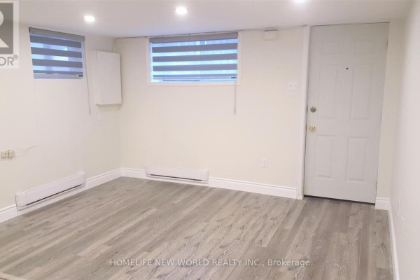Living area in basement with wood-look flooring, two windows with blinds, and a door. - Bsmt - 158 Coxwell Avenue, Toronto