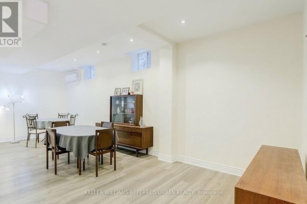 Dining area with table, chairs, and wooden storage cabinet against a plain wall - Bsmt - 161 Vanda Drive, Vaughan