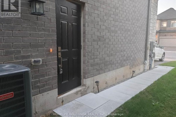 Side exterior door with dark gray brick walls and a concrete walkway leading to the door. - Bsmt - 163 Franklin Trail, Barrie