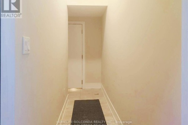 Narrow beige hallway with a closed white door at the end and a dark gray rug. - Bsmt - 163 Franklin Trail, Barrie