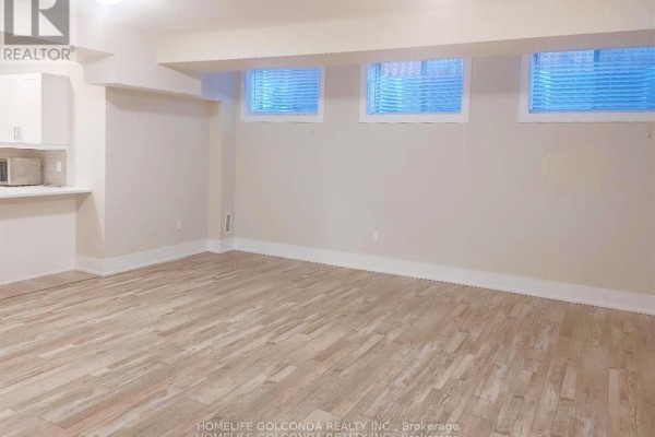 Bright basement living area with light wood floors, white walls, and three small windows. - Bsmt - 163 Franklin Trail, Barrie