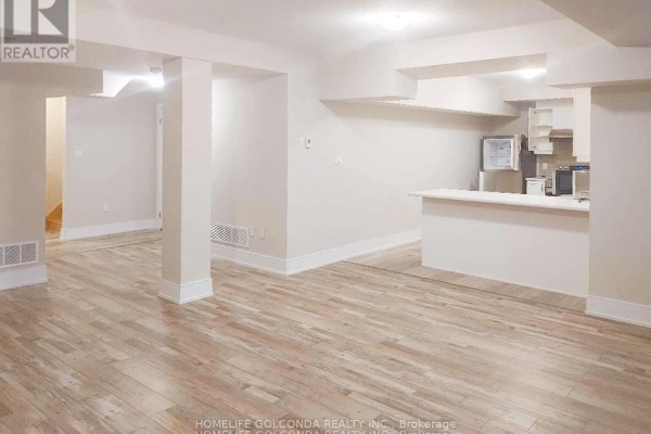 Open concept basement with light wood floors, white walls, kitchen counter, and a doorway to stairs. - Bsmt - 163 Franklin Trail, Barrie