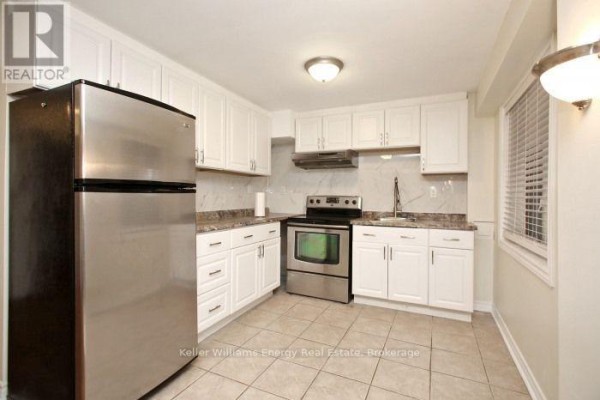 Close-up of a basement kitchen with white cabinets, granite countertops, stainless steel appliances, and tiled floor. - Bsmt - 1646 Quail Run Drive, Oshawa