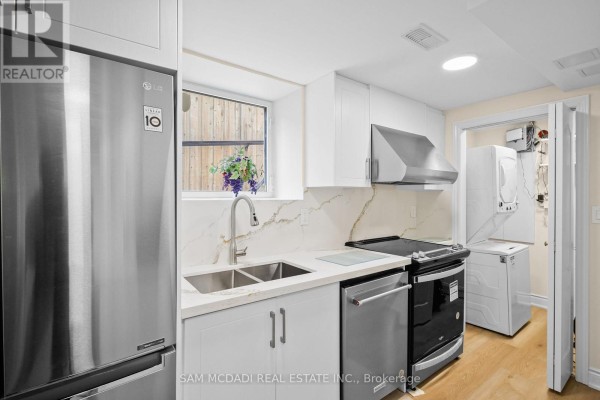 Compact basement kitchen with white cabinets, stainless steel appliances, and a stacked washer and dryer. - Bsmt - 1770 Fellen Place, Mississauga