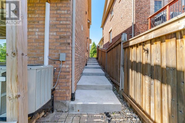 Concrete steps leading down between a brick house and a wooden fence. - Bsmt - 18 Intrigue Trail, Brampton